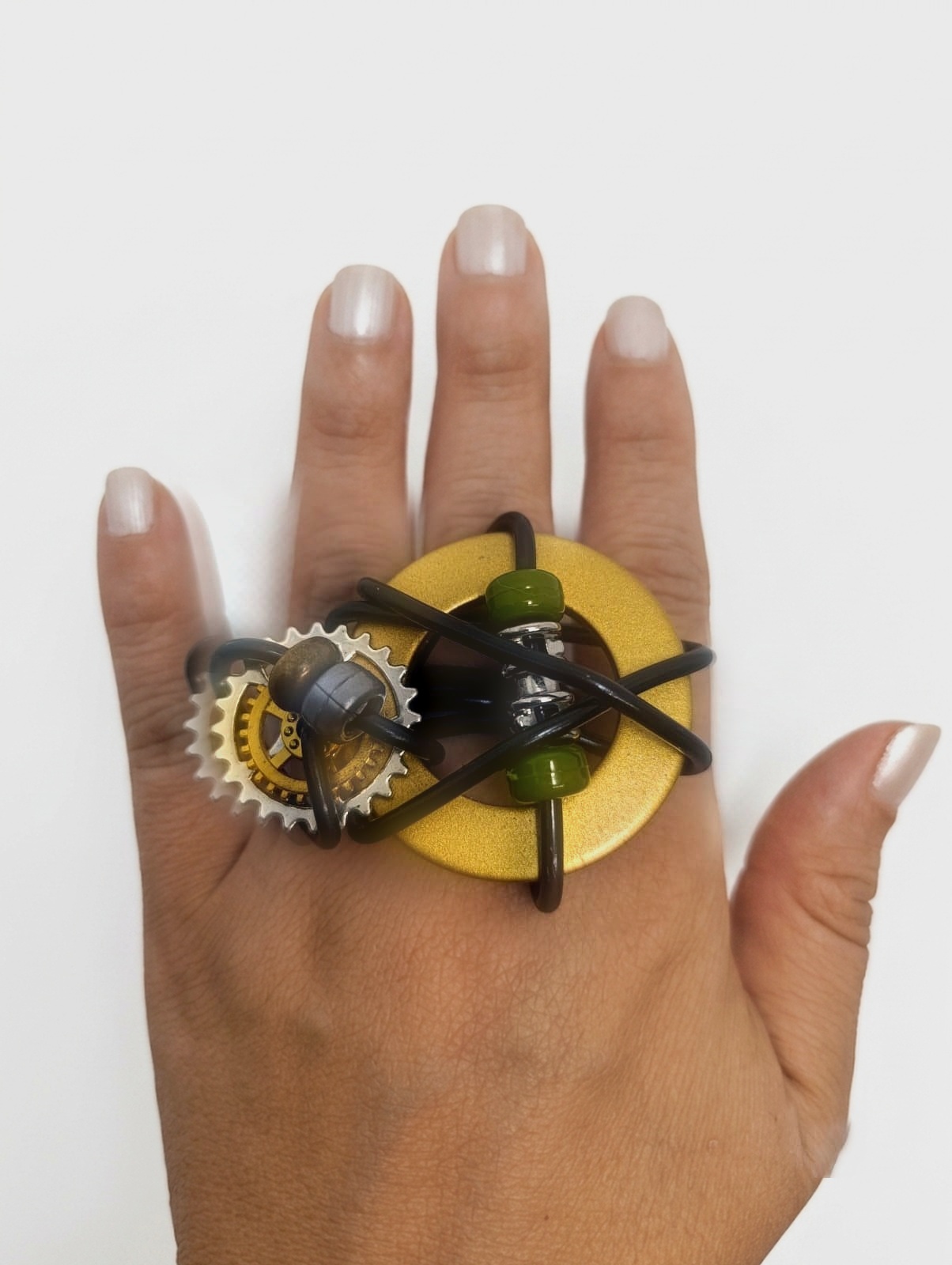 Anillo V&oacute;rtice grande sobre engranaje dorado en la mano